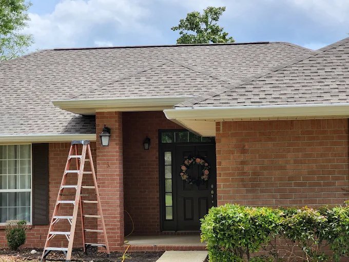 White seamless gutters installed above the front entry of a brick home.
