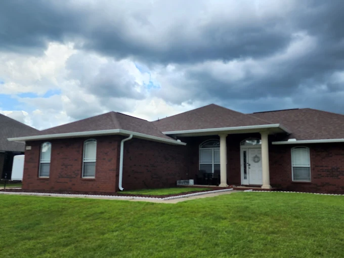 Finished seamless gutter installation on a red brick residence with a wide roofline.