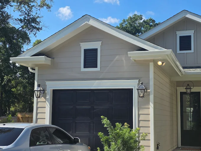 White gutter and downspout installation on a two-story home and garage.